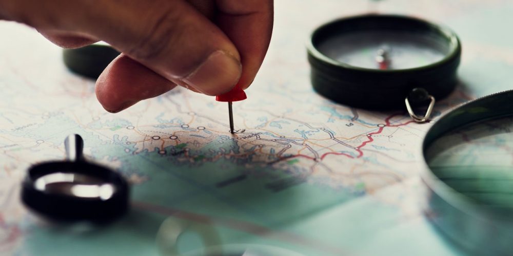 hand-putting-a-pin-on-a-paper-map